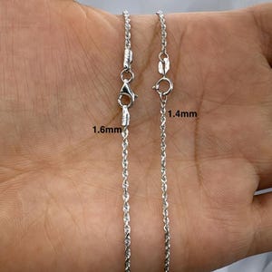 K&ouml;nnte beinhalten: Zwei silberne Seilketten, eine 1,4 mm und eine 1,6 mm dick, werden auf einer Hand gezeigt. Die Ketten sind beide silberfarben und haben eine seilartige Textur.