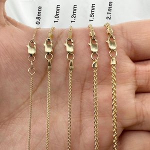May include: Five gold chains of different thicknesses, ranging from 0.8mm to 2.1mm, are displayed on a hand. The chains are all the same length and are made of a shiny gold metal.