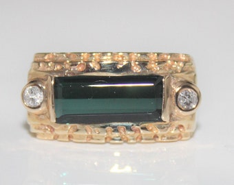May include: A gold ring with a green gemstone and two small diamonds. The ring has a textured band.