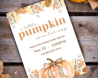 May include: Baby shower invitation featuring a watercolour pumpkin design. The invitation text reads "a little pumpkin is on her way" and includes the date, time, and location. The invitation is on a wooden background with pumpkins and leaves.