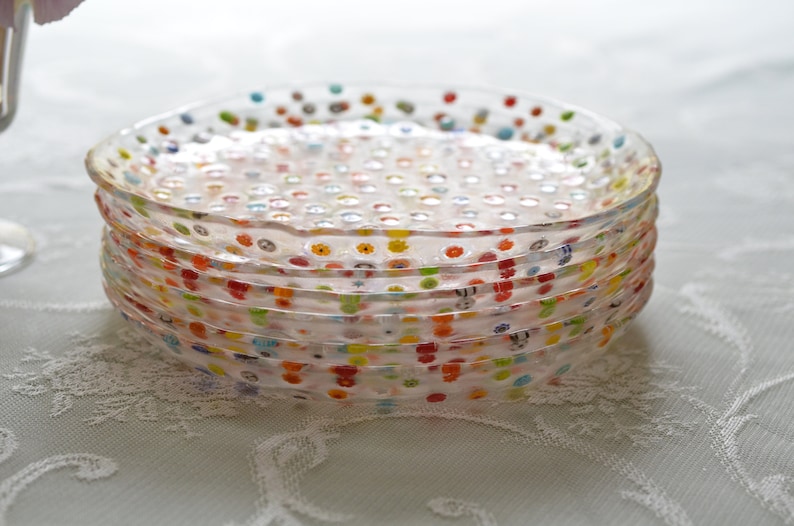 Puede incluir: Una pila de platos de vidrio transparente con lunares de colores. Los platos tienen un borde ligeramente ondulado y est&aacute;n apilados uno encima del otro. Los puntos son de varios colores, incluyendo rojo, amarillo, azul y verde. Los platos son un art&iacute;culo decorativo.