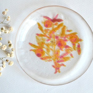 Plato de vidrio transparente pintado a mano con patrón botánico.