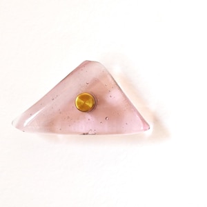 Può includere: Un pomello triangolare in vetro rosa chiaro con un centro color ottone. Il pomello ha una forma unica e una consistenza a bolle. L'hardware è un elemento decorativo per mobili.