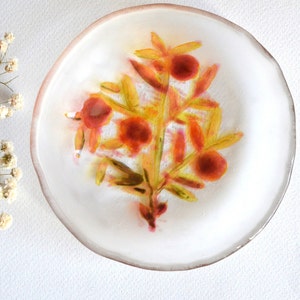 Plato de vidrio transparente pintado a mano con patrón botánico.