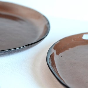 May include: Two brown ceramic plates with a slightly rippled edge. The plates are glazed with a dark brown glaze.