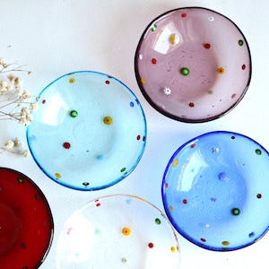 Può includere: Cinque piccole ciotole di vetro con pois colorati. Le ciotole sono in tonalità di blu, rosso, rosa e bianco.