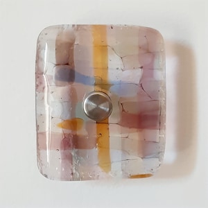 May include: A rectangular glass cabinet knob with a mosaic design in shades of pink, yellow, and blue. The knob has a stainless steel center and is likely used for furniture or decor.