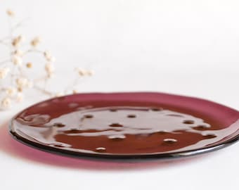 Platos de cristal de Murano color burdeos con incrustaciones de millefiori en tonos negros, turquesas y rojos, vajilla colorida.