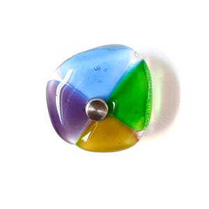 Könnte beinhalten: Ein bunter Glasgriff mit einem Edelstahlmittelstück. Der Griff ist in vier Bereiche unterteilt: blau, lila, grün und gelb. Das Glas hat ein strukturiertes Aussehen und ist vor einem weißen Hintergrund platziert.