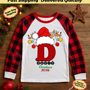 May include: A long-sleeved Christmas pajama top with a red and black plaid pattern on the sleeves. The white front features a large red letter "D" with a Santa hat and reindeer antlers. The name "DAVID" and "Christmas 2025" are printed below.