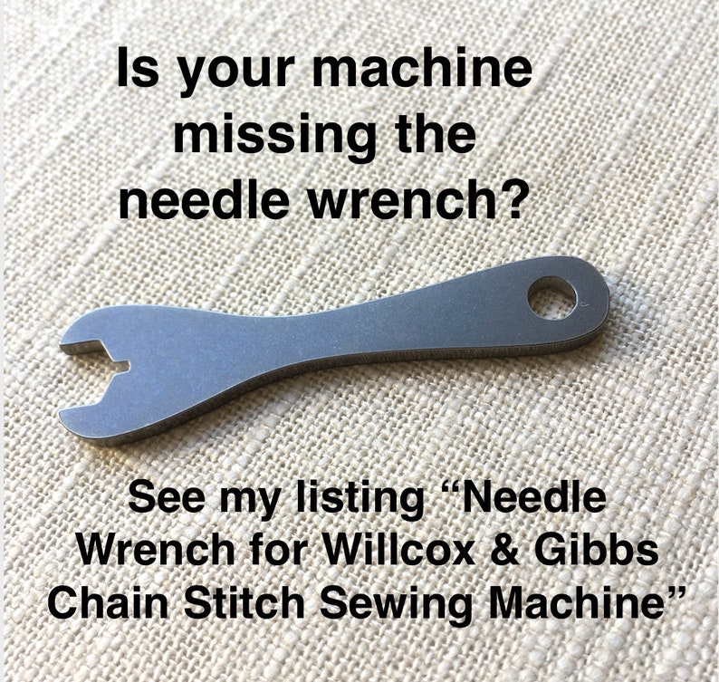 Puede incluir: Una llave de aguja plateada para una m&aacute;quina de coser. La llave tiene un agujero en el mango y una abertura en forma de U en un extremo. El texto "Is your machine missing the needle wrench? See my listing "Needle Wrench for Willcox & Gibbs Chain Stitch Sewing Machine" es visible en la imagen.
