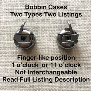 May include: Two silver bobbin cases for a sewing machine. The cases are designed to be placed in a finger-like position at either 1 o'clock or 11 o'clock. The text "Bobbin Cases Two Types Two Listings" is at the top of the image. The text "Finger-like position 1 o'clock or 11 o'clock Not Interchangeable Read Full Listing Description" is at the bottom of the image.