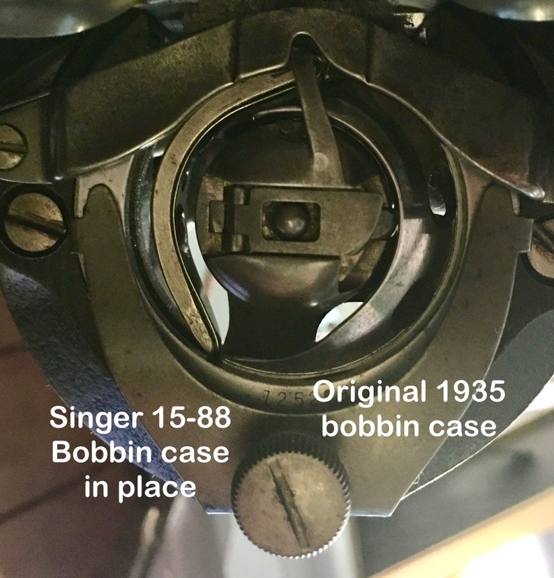 May include: Close-up of a Singer 15-88 bobbin case in place. The case is silver and has a small screw on the side. The text "Original 1935 bobbin case" is visible below the case.