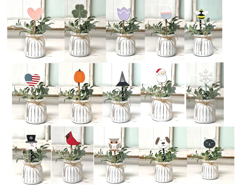May include: A set of 16 decorative plant picks featuring various designs, including hearts, pumpkins, snowflakes, and animals. The picks are inserted into small white pots with a rustic striped design.