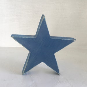 Puede incluir: Una estrella de madera azul con un acabado desgastado. La estrella es un dise&ntilde;o simple de cinco puntas.