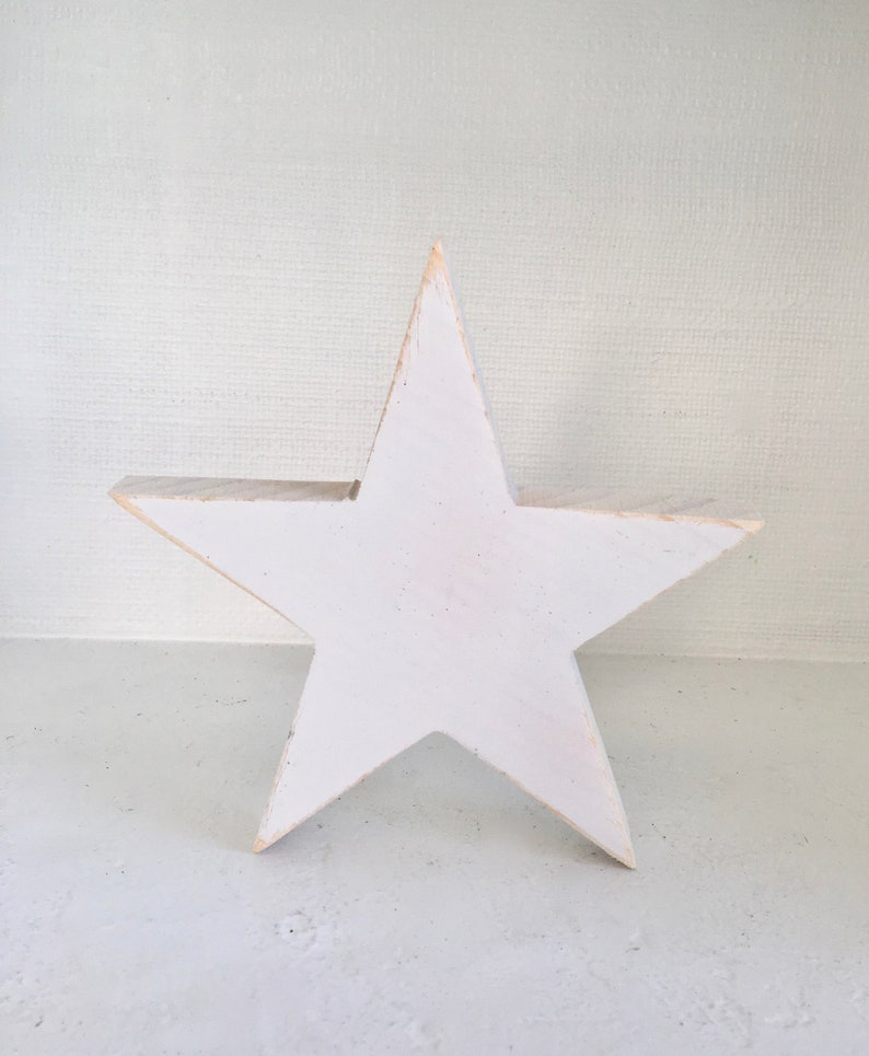 Puede incluir: Una estrella de madera blanca con un acabado r&uacute;stico. La estrella es un dise&ntilde;o simple de cinco puntas.