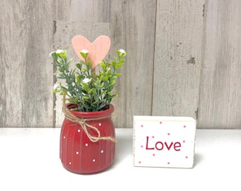 Arreglo floral para San Valentín: Jarrón con diseño desgastado, corazón de madera y letrero de amor.