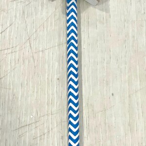 May include: A wooden star-shaped wand with a red and white starburst design and a blue star in the center. The wand has a blue and white chevron pattern.