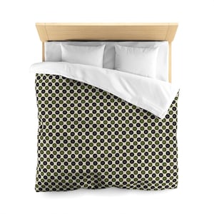 May include: Overhead view of a bed with a light wood headboard, white pillows, and a duvet cover. The duvet cover features a repeating pattern of green and black circles on a cream background. The bed is neatly made.