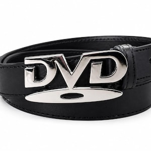 Könnte beinhalten: Ein schwarzer Ledergürtel mit einer großen, silberfarbenen Schnalle, die das Wort "DVD" bildet. Die Schnalle ist der Blickfang, die Buchstaben heben sich vom dunklen Gürtel ab. Der Gürtel ist gebogen, was darauf hindeutet, dass er getragen werden kann.