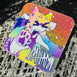 Puede incluir: Pegatina cuadrada con un personaje de dibujos animados colorido, una huella de pata y la palabra "ANIMI". El fondo tiene un degradado de arcoíris brillante.