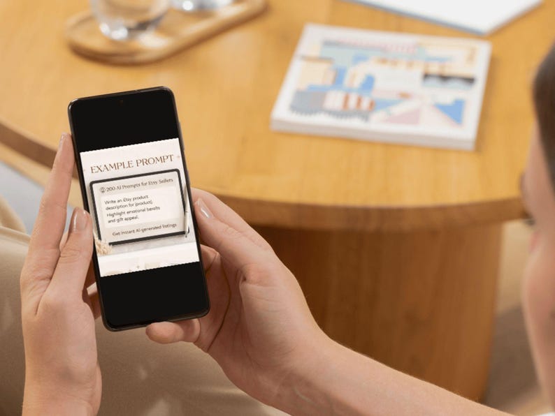 Puede incluir: Un tel&eacute;fono inteligente muestra el texto "EXAMPLE PROMPT" en la parte superior. La pantalla muestra una indicaci&oacute;n para los vendedores de Etsy, incluida la redacci&oacute;n de una descripci&oacute;n del producto, la resaltaci&oacute;n de palabras clave y la generaci&oacute;n de ahorros. El tel&eacute;fono se sostiene frente a un fondo borroso.