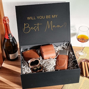 Peut inclure: Une bo&icirc;te cadeau noire avec le texte dor&eacute; WILL YOU BE MY Best Man? contenant une flasque gain&eacute;e de cuir marron, un petit &eacute;tui en cuir marron, un briquet gain&eacute; de cuir marron et une petite bo&icirc;te en bois avec des boutons de manchette.