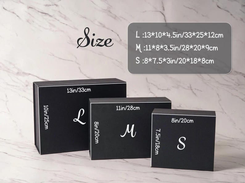 Peut inclure: Trois bo&icirc;tes cadeaux rectangulaires noires en tailles grande, moyenne et petite. Chaque bo&icirc;te porte une lettre blanche L, M ou S. Les dimensions sont indiqu&eacute;es : L mesure 33x25x12 cm, M mesure 28x20x9 cm et S mesure 20x18x8 cm.