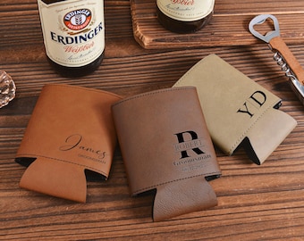 May include: Three personalized leatherette can coolers in shades of brown and tan, with black stitching. One cooler is engraved with "James Groomman", another with "Robert Groomsman 06.17.2023", and the third with "YD".