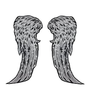Puede incluir: Dos parches bordados con forma de alas de ángel. Las alas son negras con detalles blancos y grises, con un diseño de plumas en capas. Los parches son simétricos y sobre un fondo blanco.