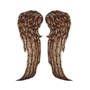 May include: A pair of brown embroidered angel wings on a beige background.