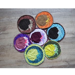 Könnte beinhalten: Sieben runde gestickte Patches mit verschiedenen Designs und Farben. Die Patches zeigen eine Halbmondform mit verschiedenen Mustern und Farben, darunter Blau, Grün, Lila, Orange und Braun.