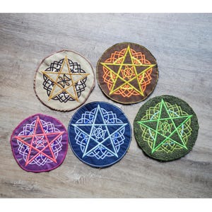 May include: Five embroidered patches featuring a pentagram design. Each patch has a different color scheme: beige with black and gold, brown with orange and yellow, purple with pink and white, navy blue with light blue and green with yellow.
