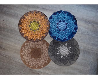 May include: Four circular floor cushions featuring intricate mandala and flower of life patterns. The top left cushion is brown with yellow embroidery, the top right is navy blue with blue, the bottom left is tan with white, and the bottom right is gray with white.