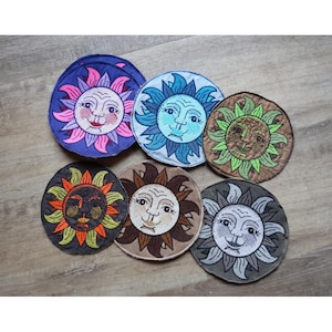 Könnte beinhalten: Sechs gestickte Patches mit verschiedenen Sonnen-Gesichtern in verschiedenen Farben und Designs. Die Sonnen-Gesichter haben verschiedene Ausdrücke, darunter lächelnd, stirnrunzelnd und neutral.