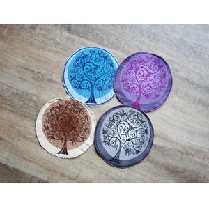 Peut inclure: Quatre écussons circulaires en tissu ornés de motifs d'arbres brodés aux branches tourbillonnantes complexes. L'ensemble comprend un bleu, un violet, un beige avec broderie marron et un gris avec broderie noire, chacun avec un bord fini.