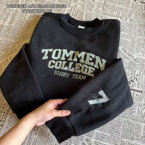 May include: Black crewneck sweatshirt with embroidered text "TOMMEN COLLEGE RUGBY TEAM" in light green. The sleeve features the number "7" and the word "Athlete" in the same color. The top reads "DESIGNED AND EMBROIDERED BY HSTHREADS".