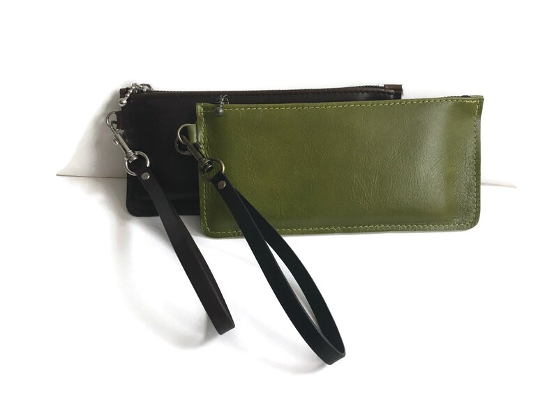 May include: Two leather pouches with black straps and silver clasps. One pouch is brown and the other is green.
