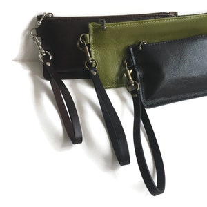 May include: Three leather zippered pouches with wrist straps. The pouches are brown, green, and black.