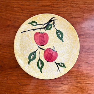 Puede incluir: Un plato de cerámica amarillo con un esmalte moteado presenta una rama de manzano negra y verde con dos manzanas rojas.