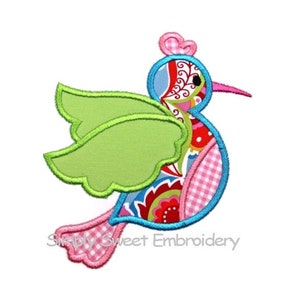 May include: A colorful applique design of a bird with green wings, a pink body, and a blue head. The bird has a pink crown and a small black eye. The design is perfect for embroidery projects.