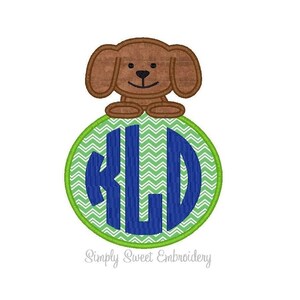 May include: A brown dog with a green and white chevron pattern circle with the letters "KLD" in blue.