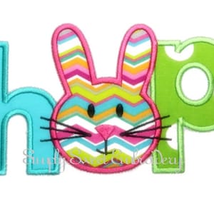 May include: An embroidered patch with the word "hop" in turquoise, green, and white. The "o" is replaced with a colorful bunny face with pink ears, a pink nose, and black whiskers.