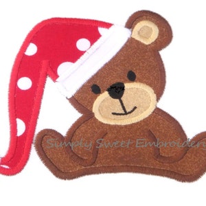 May include: A brown teddy bear wearing a red and white Santa hat with white polka dots. The bear is sitting with its legs crossed and has a happy expression on its face.