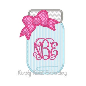 Peut inclure: Un bocal en verre à rayures bleues et blanches avec un nœud rose et le monogramme "NBE" en rose.