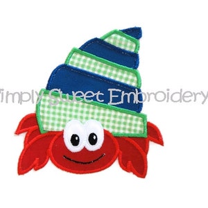 May include: Red and blue embroidered applique of a crab wearing a green and blue shell. The crab has large eyes and a smiling mouth. The text "Simply Sweet Embroidery" is visible in the background.