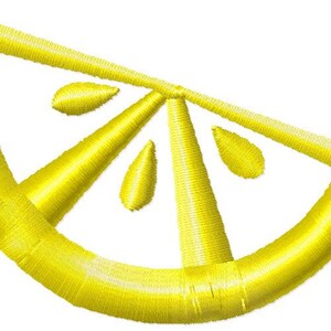 Puede incluir: Una rodaja de limón bordada de color amarillo con tres semillas. La rodaja de limón es un diseño simple con una forma curva y un extremo puntiagudo.