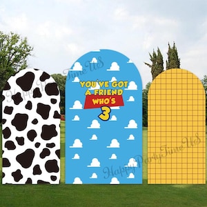 May include: Three arched backdrop panels featuring distinct patterns: a black and white cow print, a blue sky with white clouds and the text YOU'VE GOT A FRIEND WHO'S 3, and a yellow grid pattern. These decorative displays stand upright.