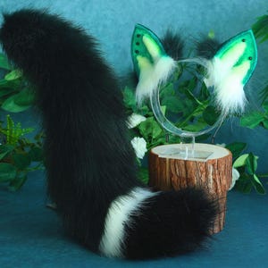 May include: A black and white faux fur tail with a white tip. The tail is attached to a headband with green and white faux fur ears.