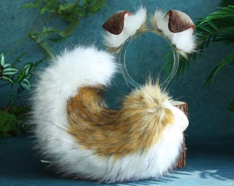 May include: A white and brown faux fur tail with a brown and white faux fur headband with brown ears. The headband is made of a clear plastic material.
